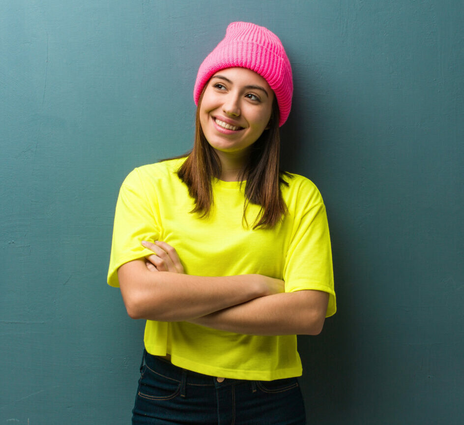 Young modern woman smiling confident and crossing arms, looking up